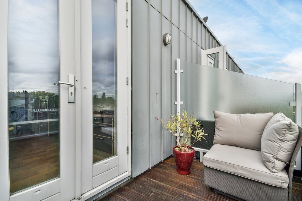 balkon z podłogą z desek i narożnikiem balkon z narożnym siedziskiem z pufami w szarym kolorze