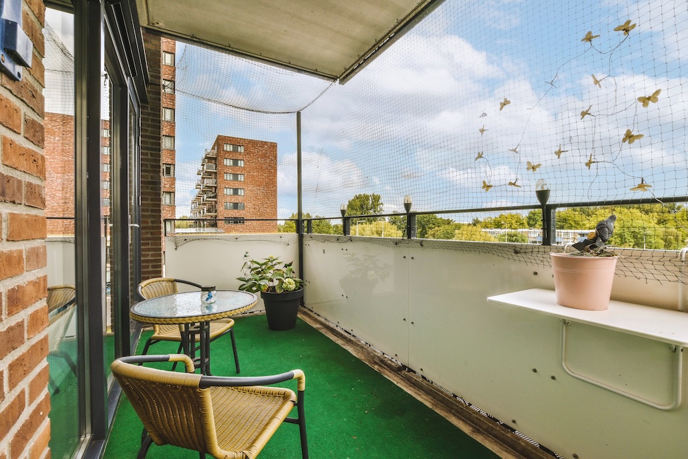 balkon z rozwijaną wykładziną imitującą trawę balkon z krzesłami i stolikiem ze szklanym blatem