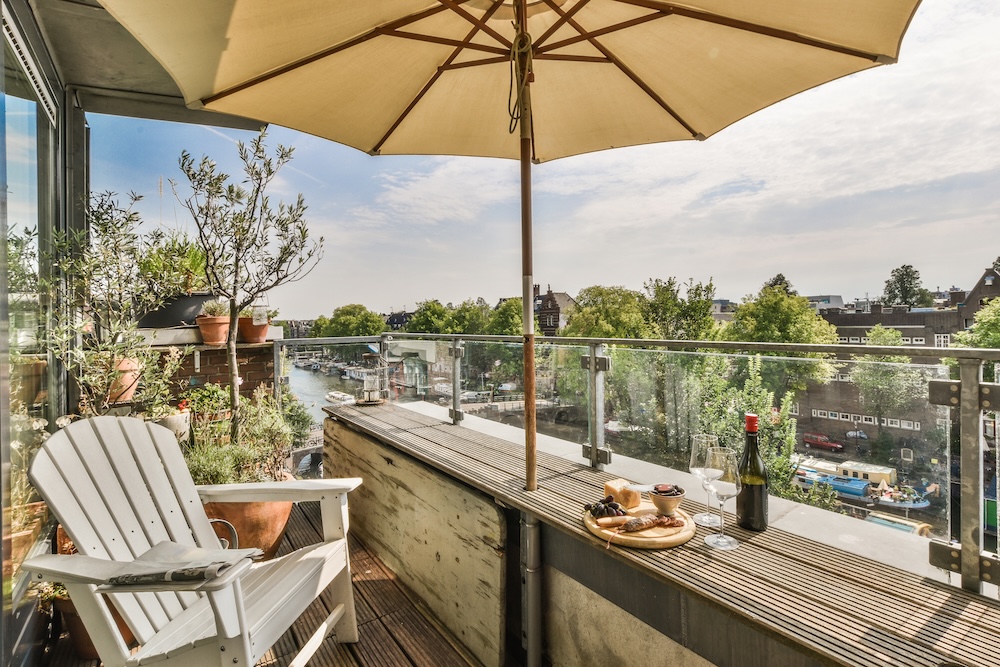 mały balkon - inspiracje z białym krzesłem i parasolem słonecznym mały balkon - inspiracje z roślinami w rogu i parasolem przy krześle