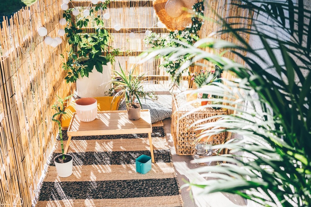 mały balkon - inspiracje z bambusowym stolikiem i poduszkami na ziemi mały balkon - inspiracje z roślinami i dywanem
