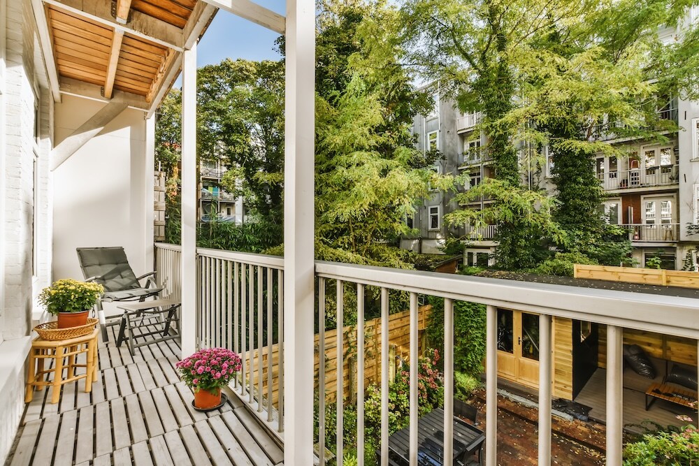wąski balkon z dwiema roślinami i stolikiem balkon z dwoma kwiatkami i krzesłem