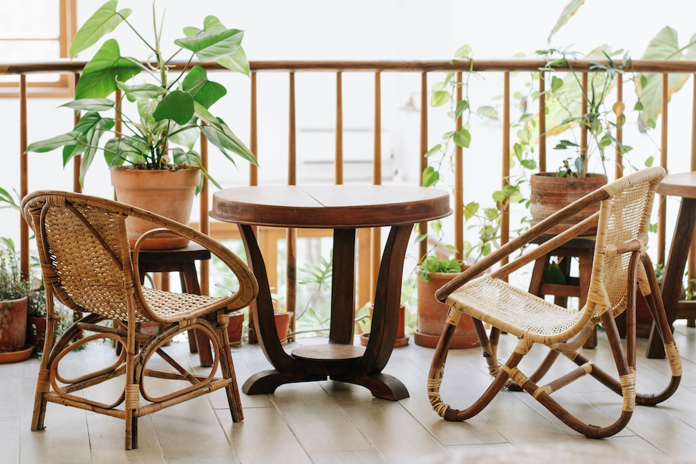 balkon urządzony z drewnianymi meblami i roślinami drewniany stół i dwa krzesła z naturalnych materiałów na balkonie